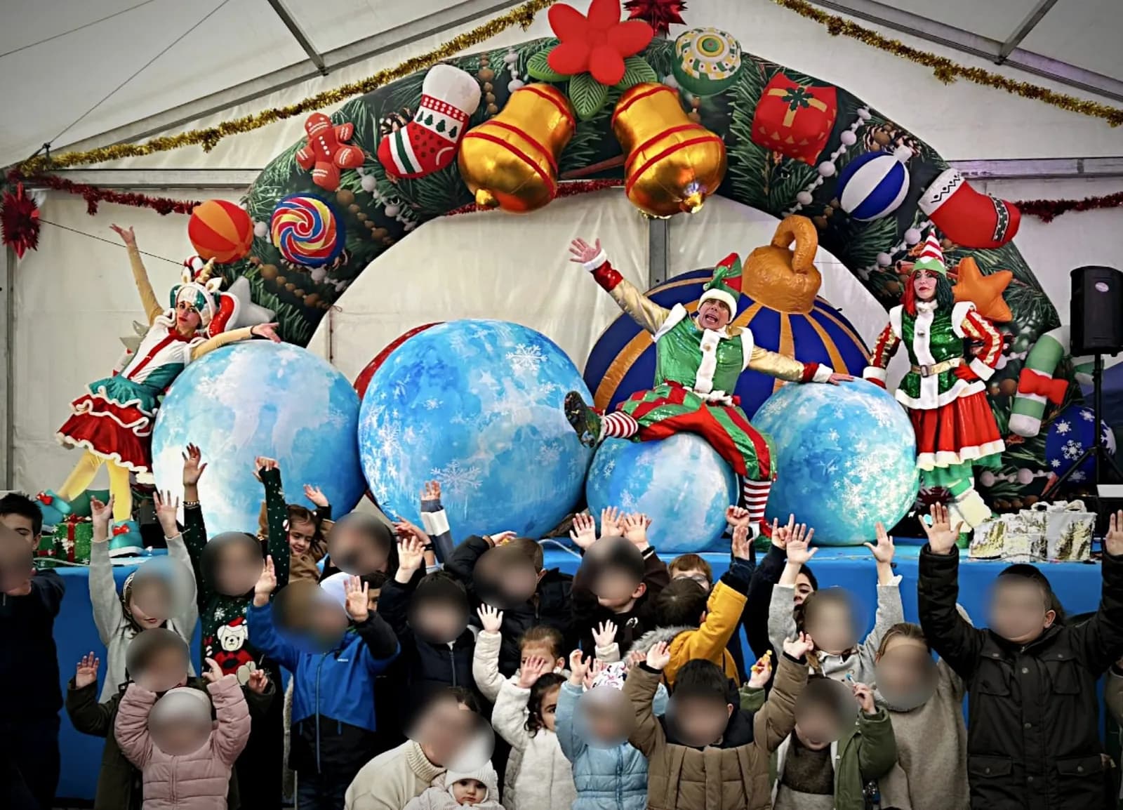 Elfos sobre bolas gigantes azules bajo un arco navideño